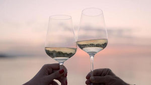 Twee glazen prosecco uit de prosecco proeverij tegen een pastelkleurige zonsondergang